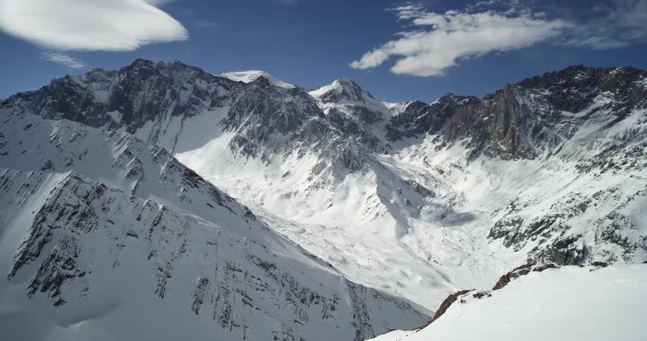 Shadow covers part of large snowy mountain standing under cloudy sky