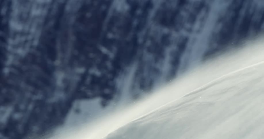 Snow and ice blowing in the wind with frost and rock in the background