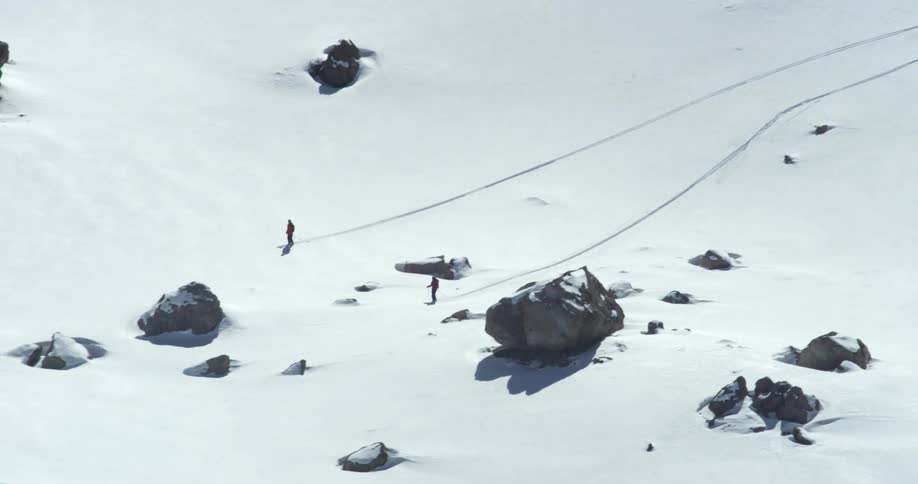 Skiers glide through a snowy field full of rocks