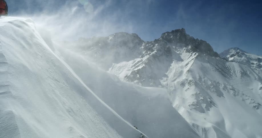 Heavy wind is blowing snow off of the mountain tops