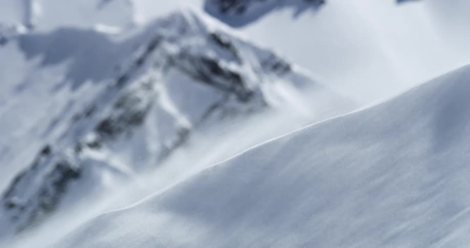 Wind blowing over snow in mountains like a sand dune