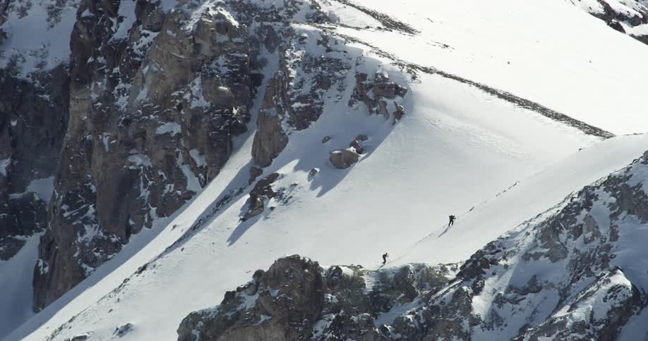 Two people climbing up a snowy mountain