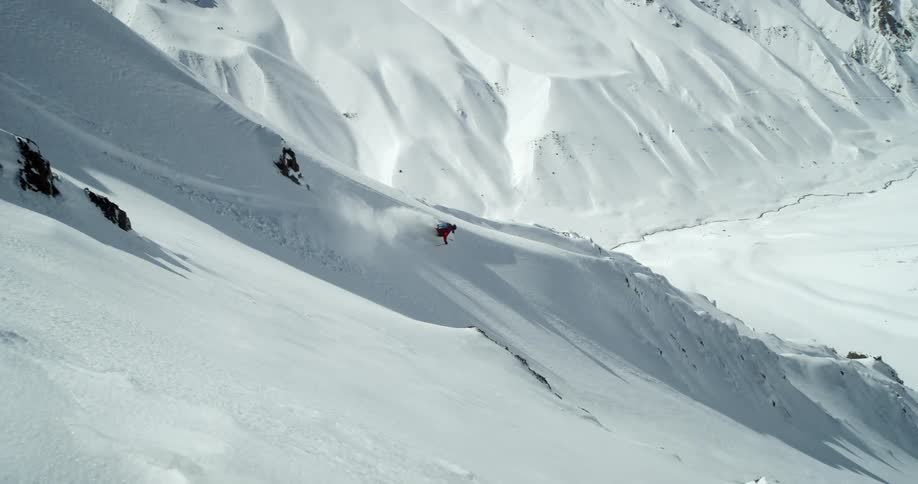 A skier drops into a steep big mountain slope