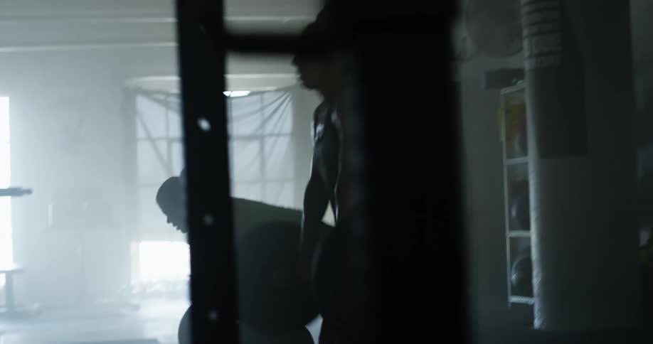 Two woman in a gym lifting weights with windows in the background