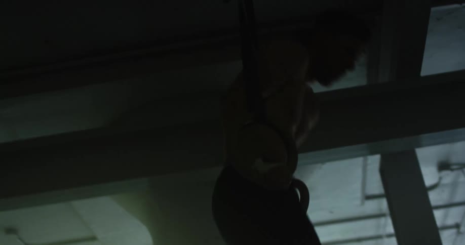 A male caucasian swinging on gymnastics hoops in a gym