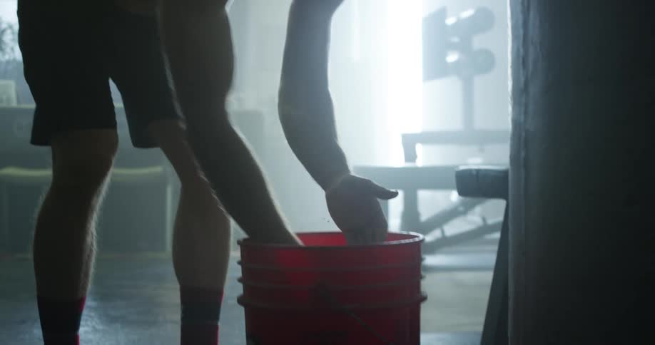 A man puts athletic chalk on his hands in a gym setting