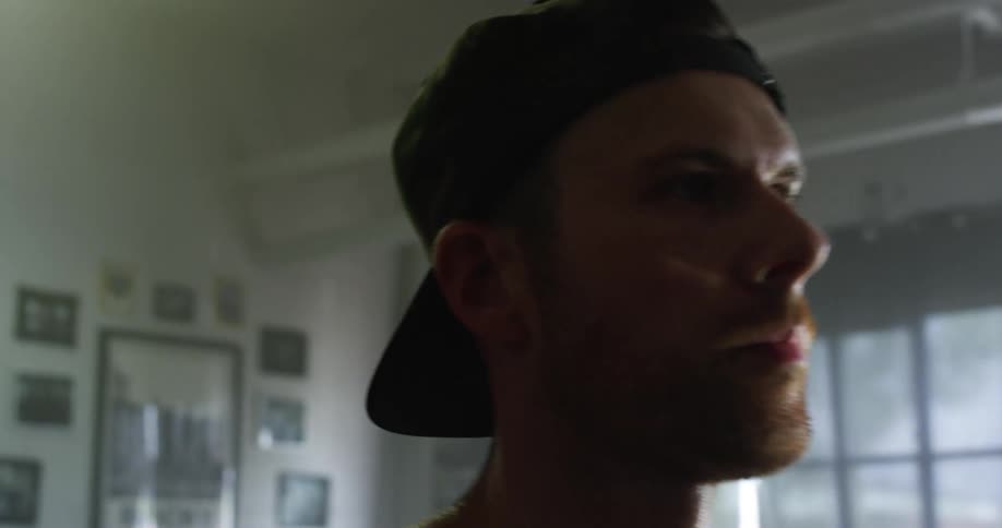 Man with a cap and a beard takes a break during workout in gym