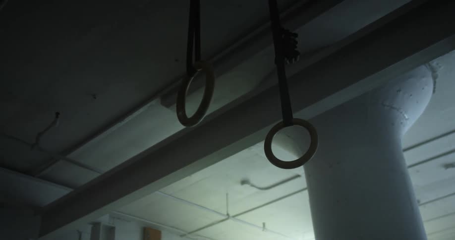 A room with gymnastic rings and flashing lights with a pillar in the background