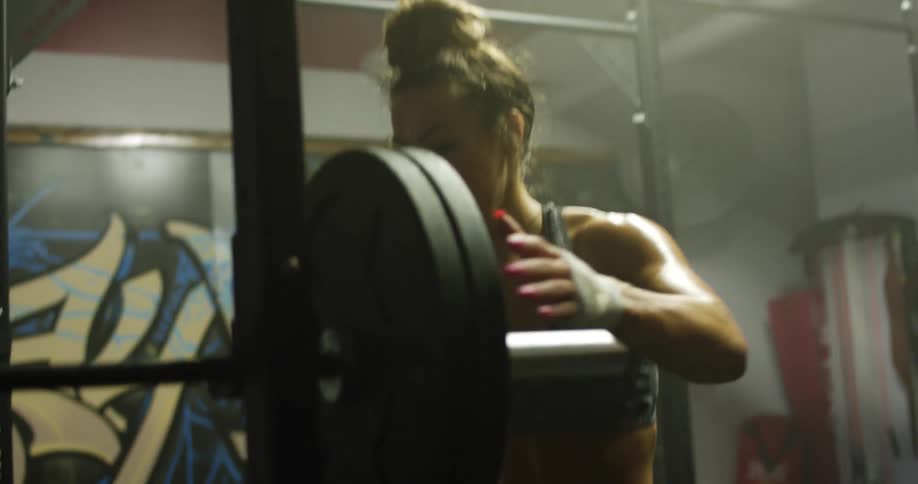 A female athlete takes the weight off a bar in a gym