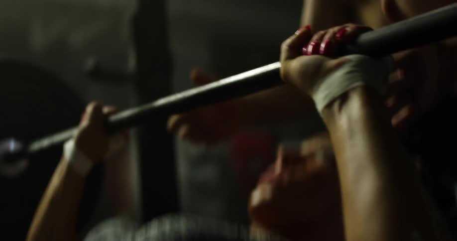 A man spots a woman as she bench presses weights