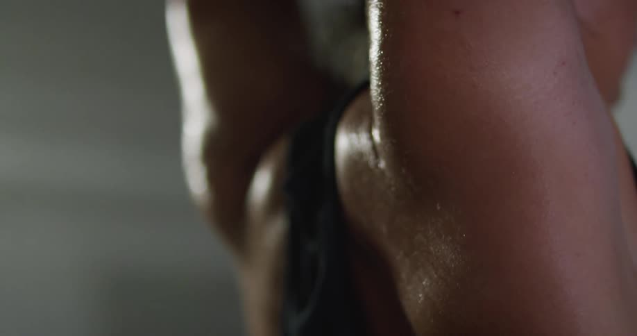 A woman in the gym stretching with sweat on her back