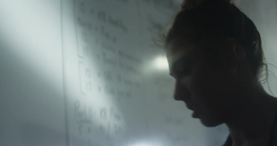 Woman with a top knot hair cleans a whiteboard with a rag