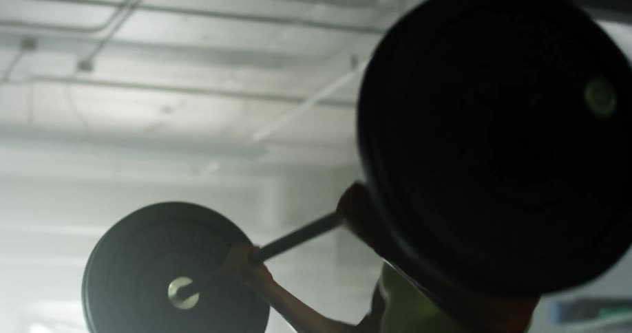 Woman sweats heavily as she lifts weights in gym