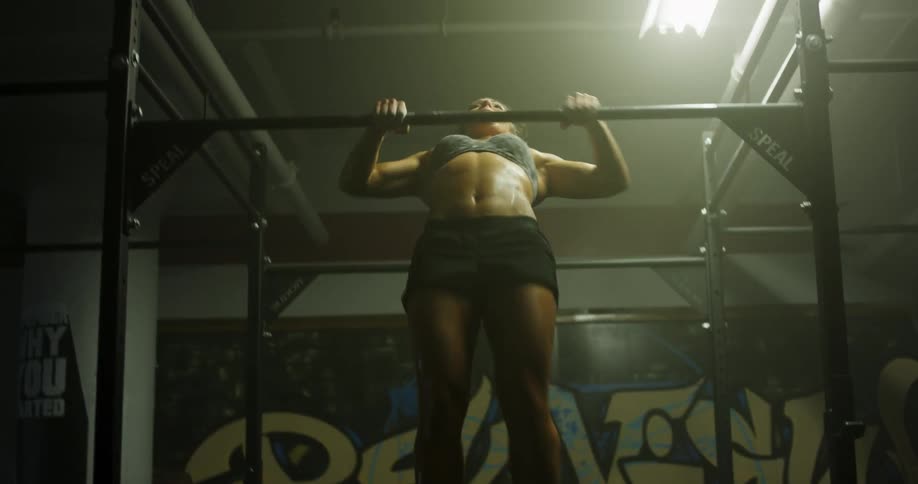 Muscular woman does pull ups in a gym