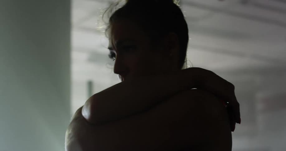 Woman wearing sports bra stretches in dimly lit gym