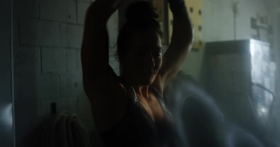 A woman is stretching in the dark garage