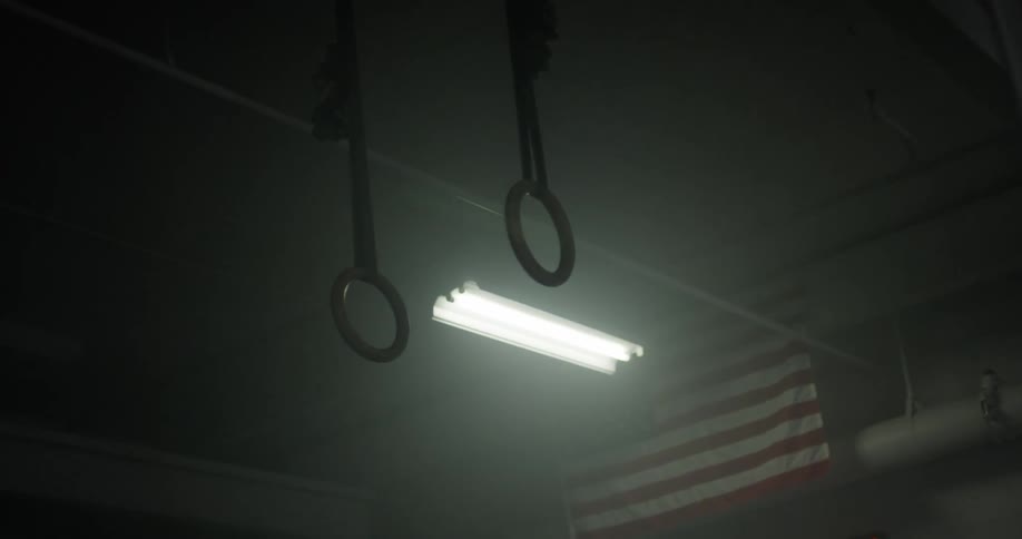 A gym with lights a digital clock gymnastic rings and an american flag