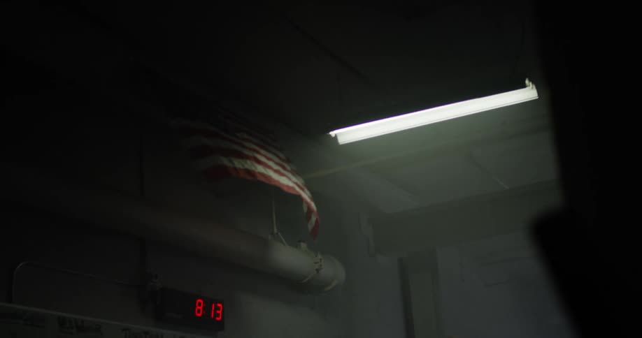 An american flag waves as it hangs from the wall in a dimly lit room