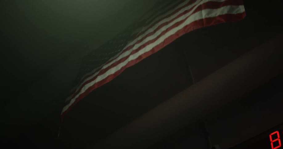 An american flag waves as it hangs from the ceiling of a dimly lit room