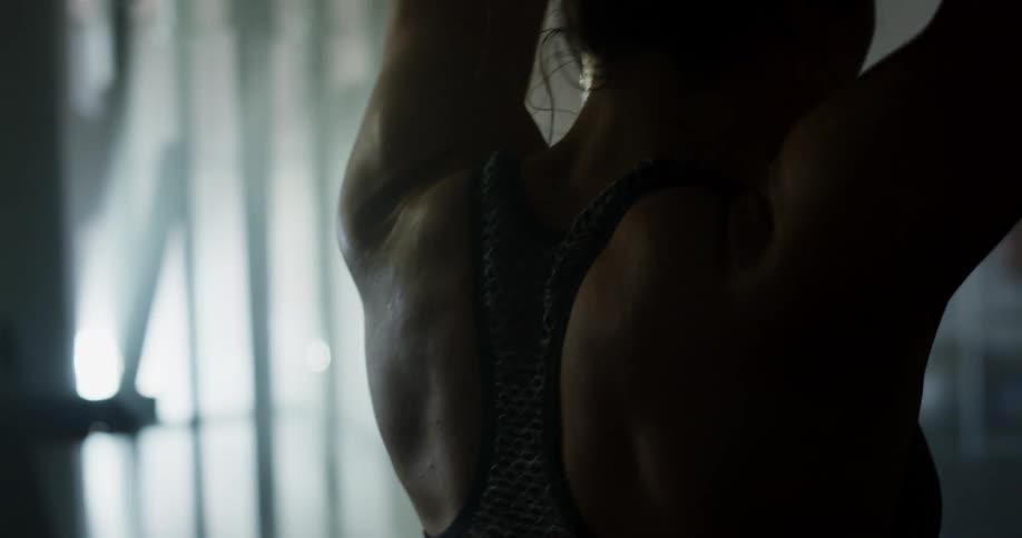A woman in a room stretching with exercise equipment and a window in the background