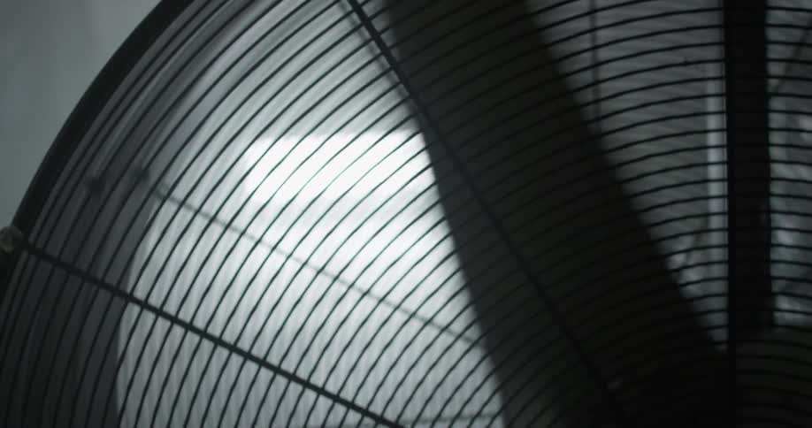 A large industrial fan has its blades spinning at first before it winds down and the blades come to a rest