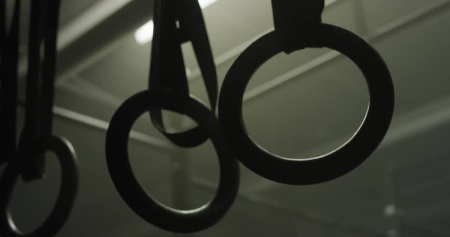 The rings are hanging in the dark gym