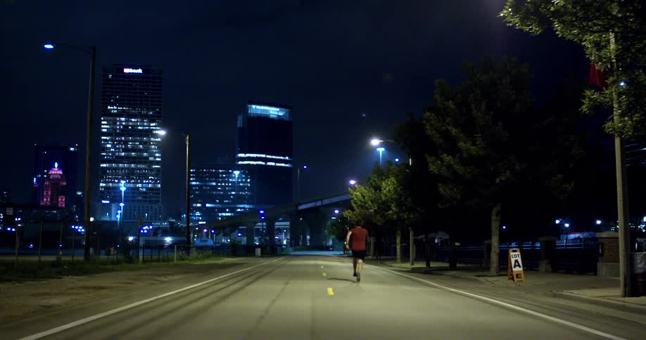 A man is jogging in a city at night