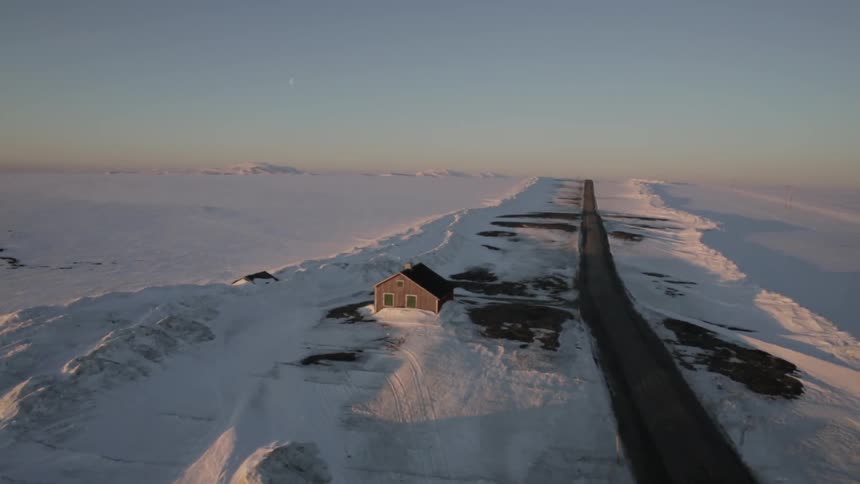Aerial view of a home, road and fields covered with snow