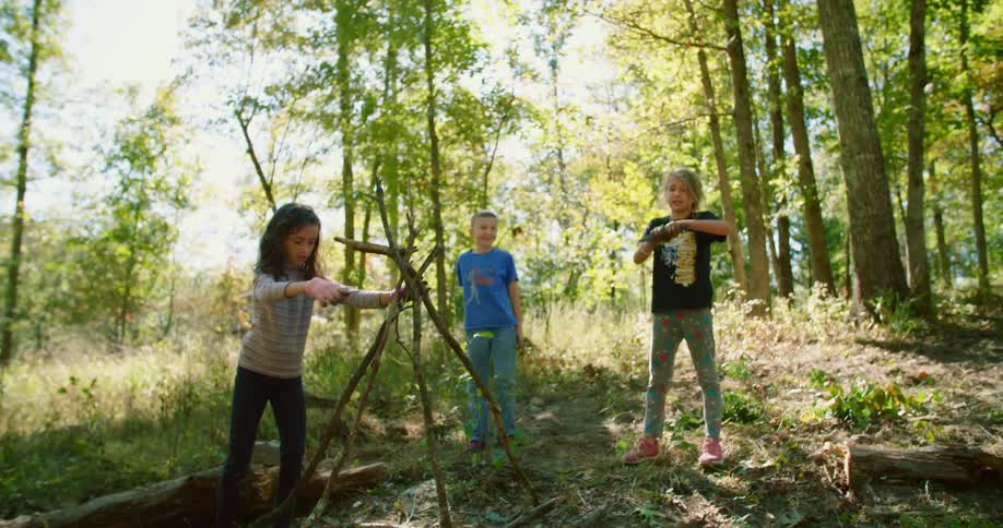 Three children play on the hill near the forest