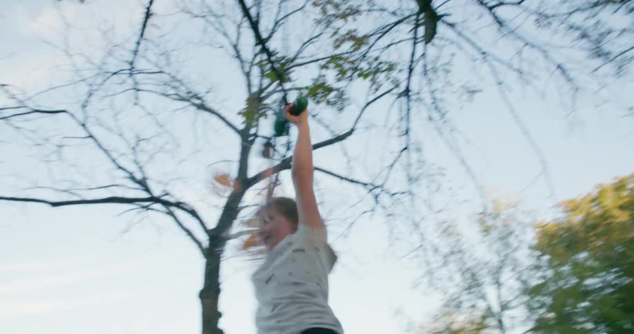 A little girl holds on to a rope on a tree and swings around