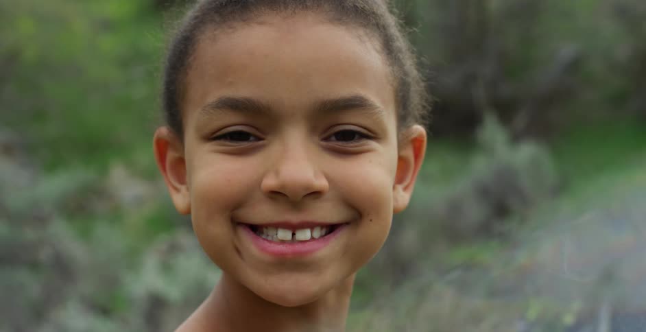 A little girl outside smiles for a photo