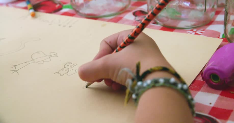 A child using a pencil to draw animals on a piece of paper