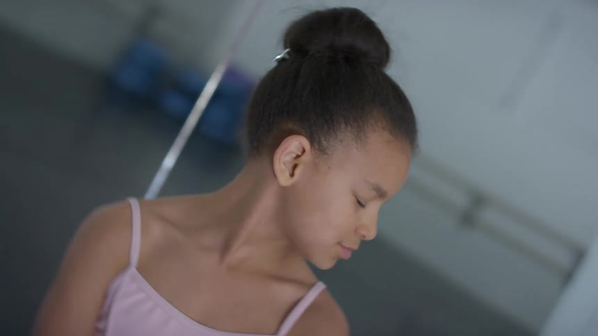 A female child wearing a leotard standing in a dance studio