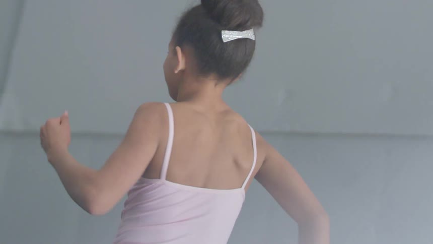 A little girl dancing inside a building
