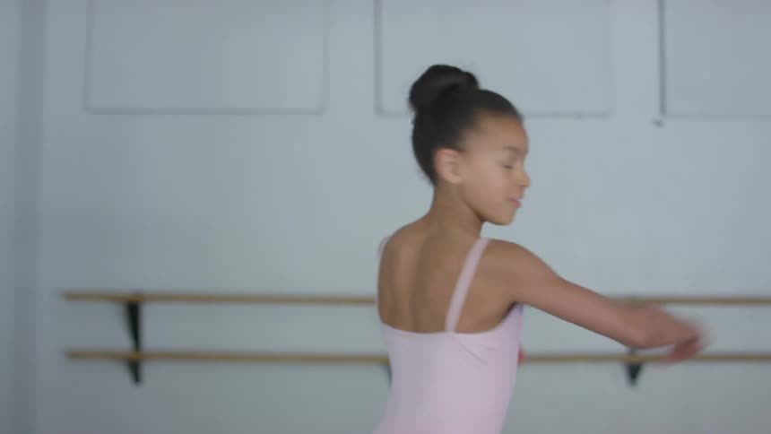 Child ballerina with a pink dress performs ballet in dance studio