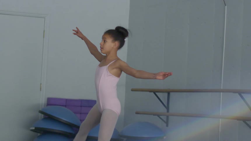 A young ballerina performs a dance in a ballet school