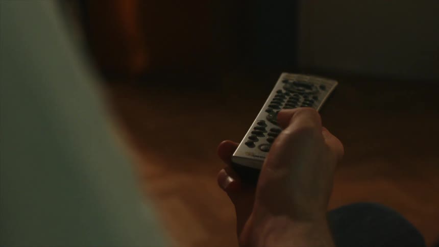 A man using his hand to tap a remote control