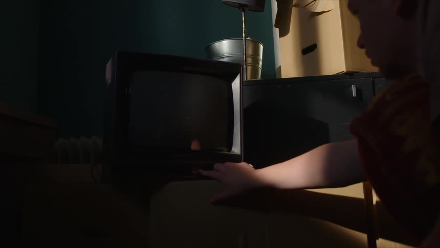 A man leans over to turn the tv on