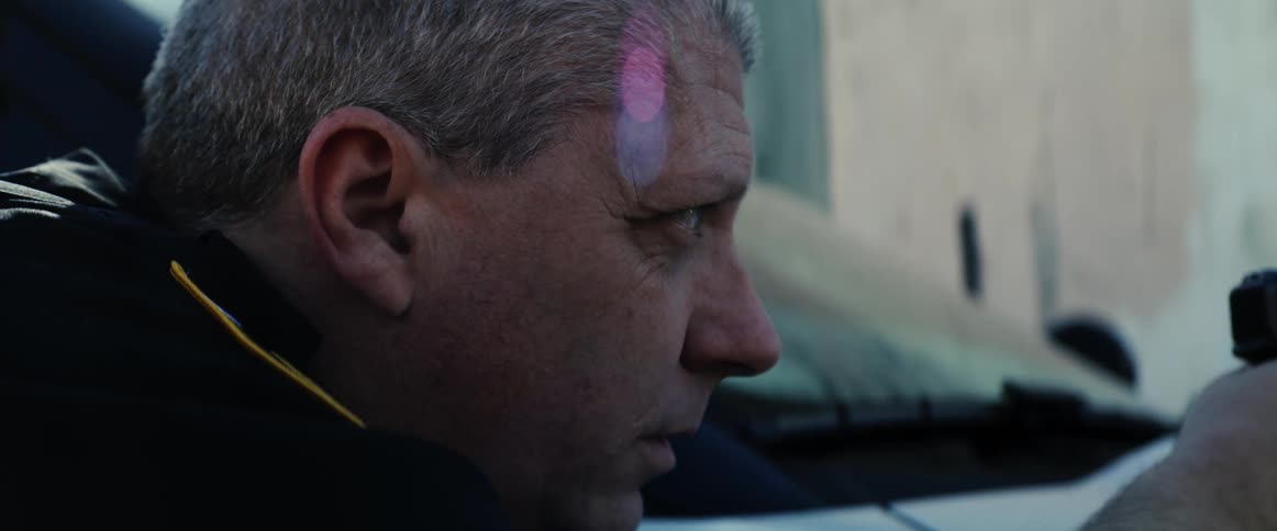 A police officer hides behind a vehicle with his gun drawn