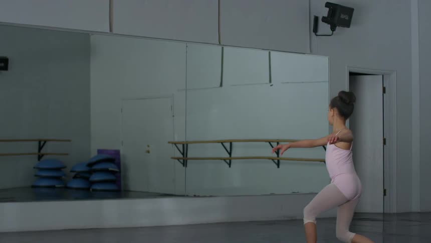 A girl spinning and dancing in a dance studio in front of a mirror