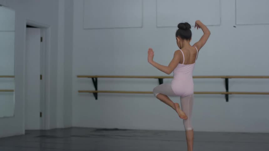 A girl with a leotard jumping and dancing in a dance studio