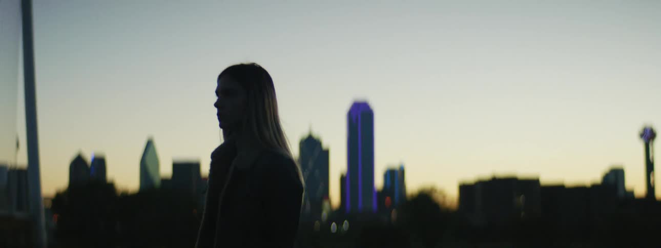 Woman walking around is silhouetted against the skyline at dusk