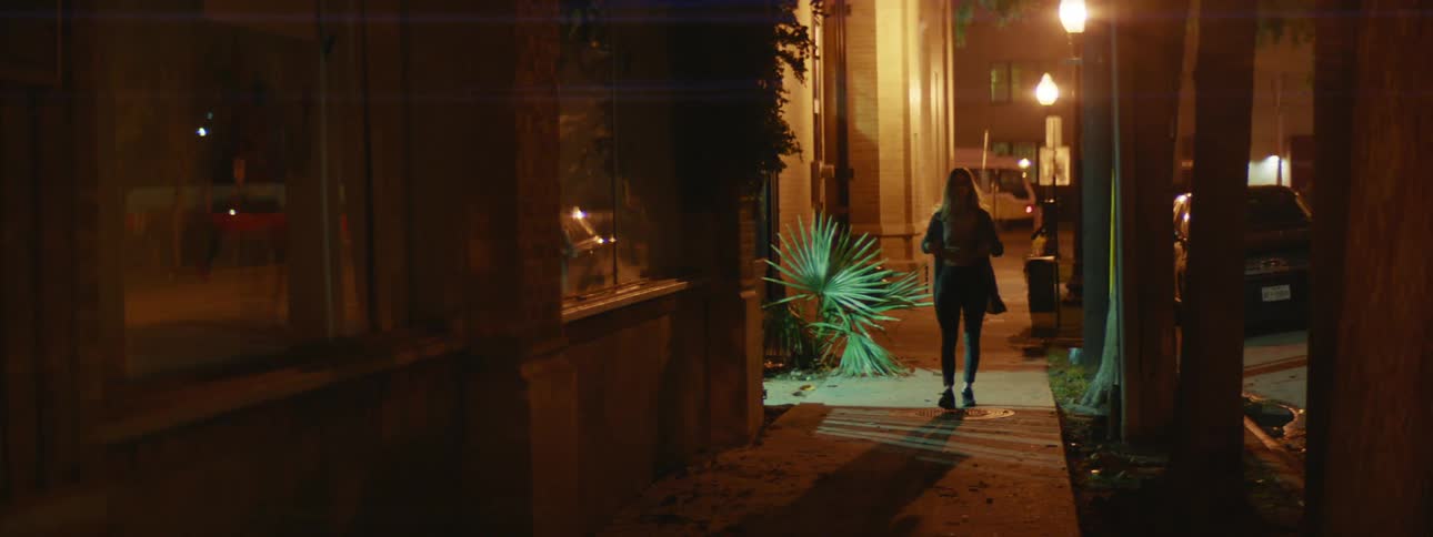 A woman is walking in a city at night