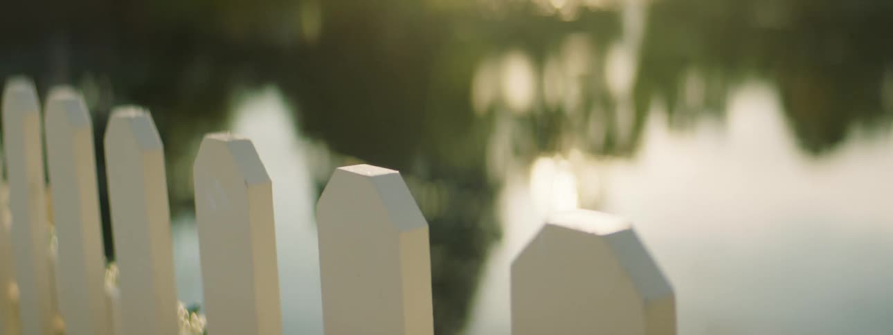 White picket fence stands next to the lake