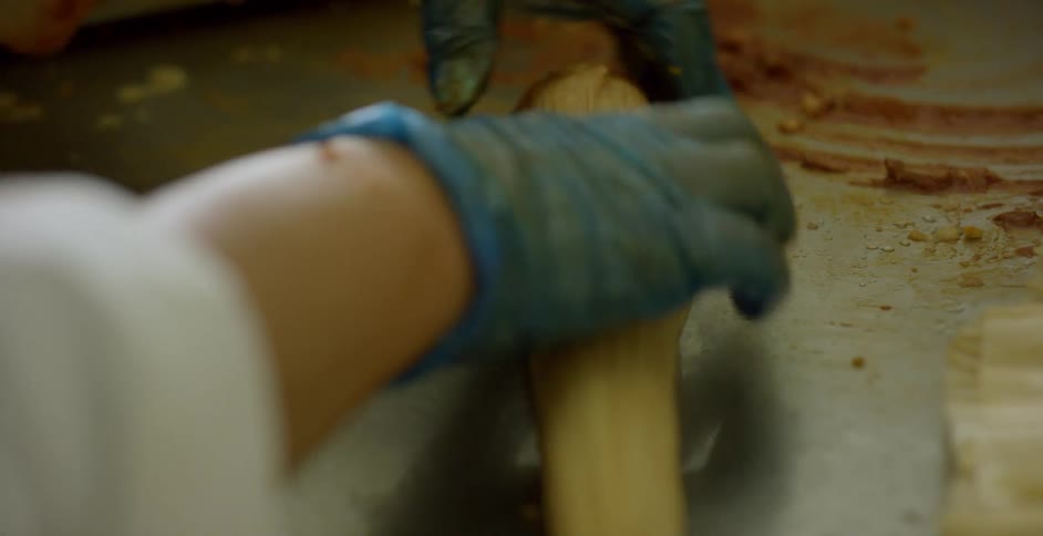 A restaurant worker rolling up a tamale on a metal table