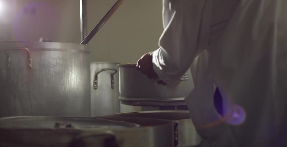 Two men lifting a heavy pot in a factory
