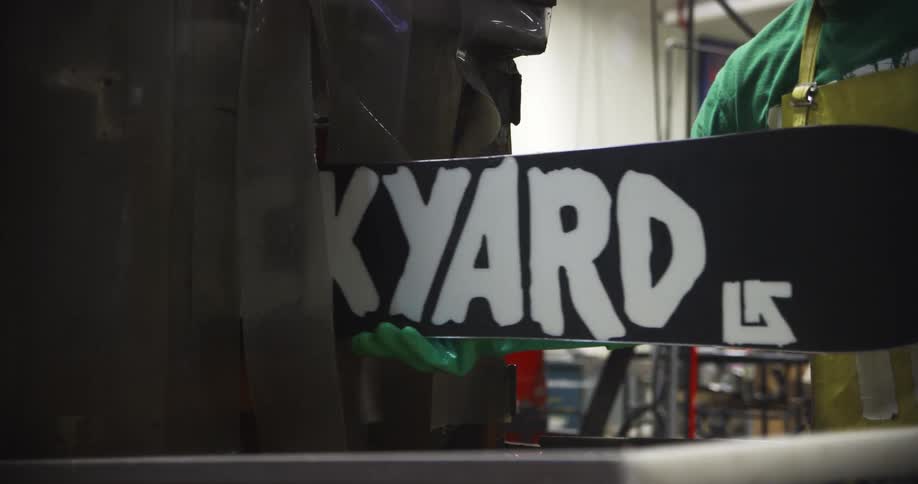 A worker pulling a snowboard out of a machine