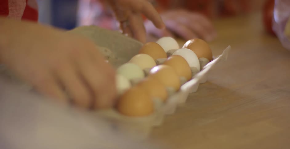 Person picks up one egg of various kinds available in carton and examines it