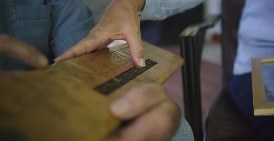 Person examines name plaque with braille writing