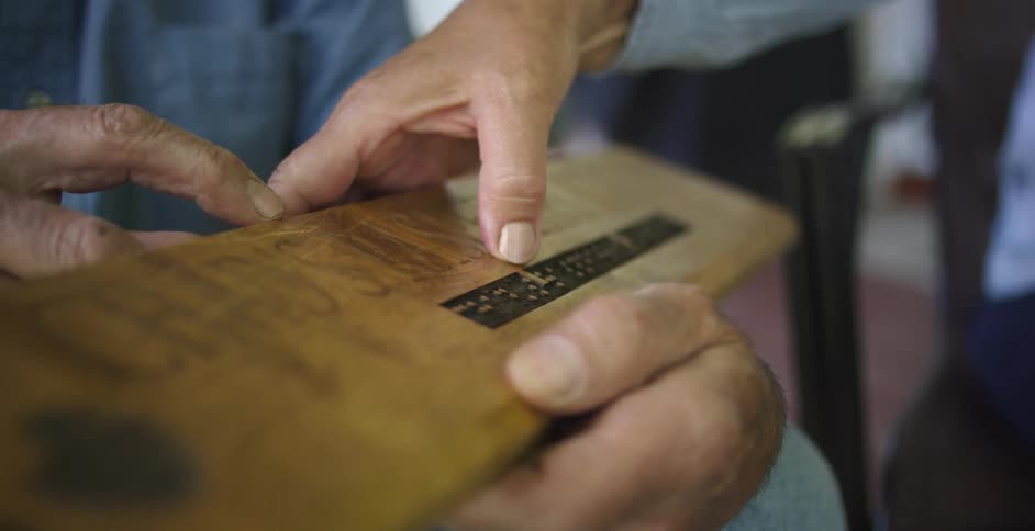A man holds a sign and another man runs his fingers over it